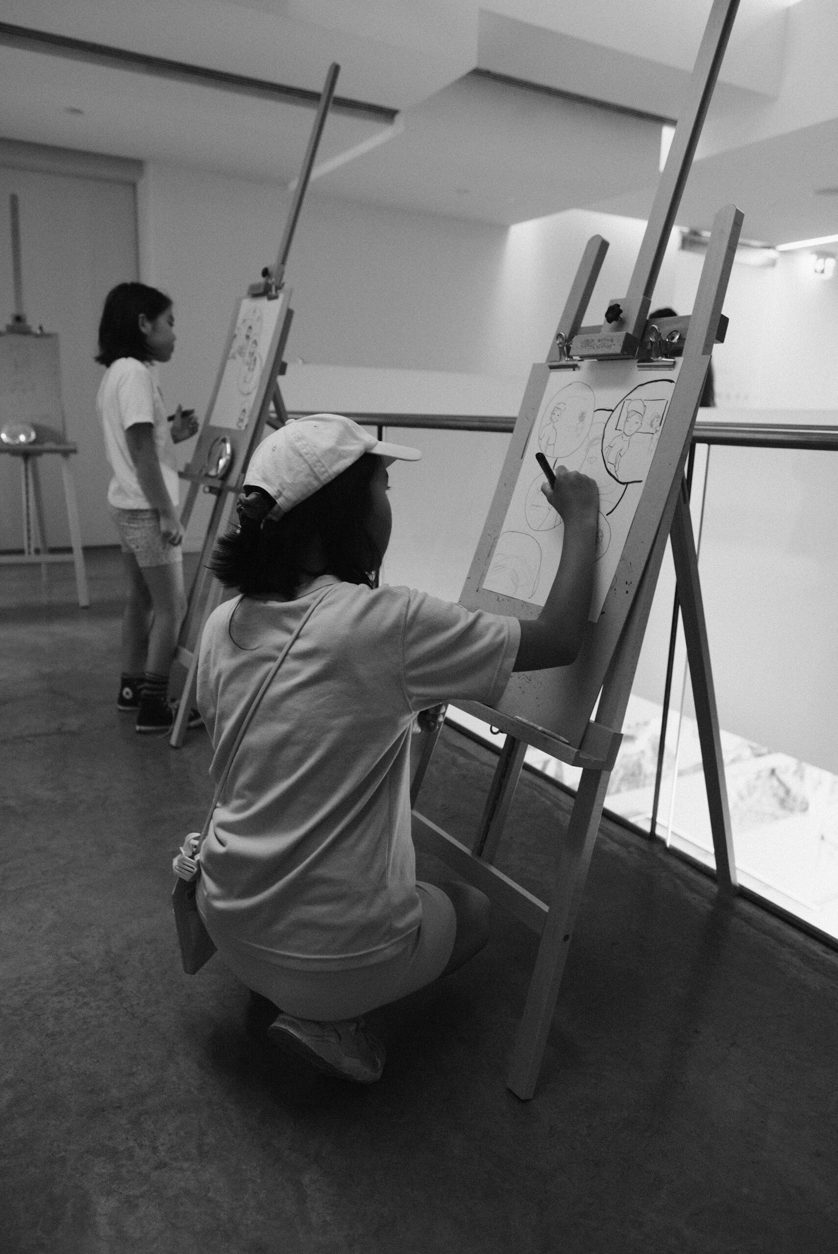 A woman sitting on the ground drawing on a wall